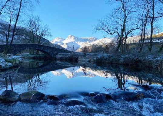 View along Great Langdale Beck to the Langdales covered in snow.